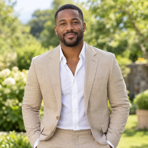 Man in a tan linen suit and open-collar white shirt, dressed as a summer wedding guest