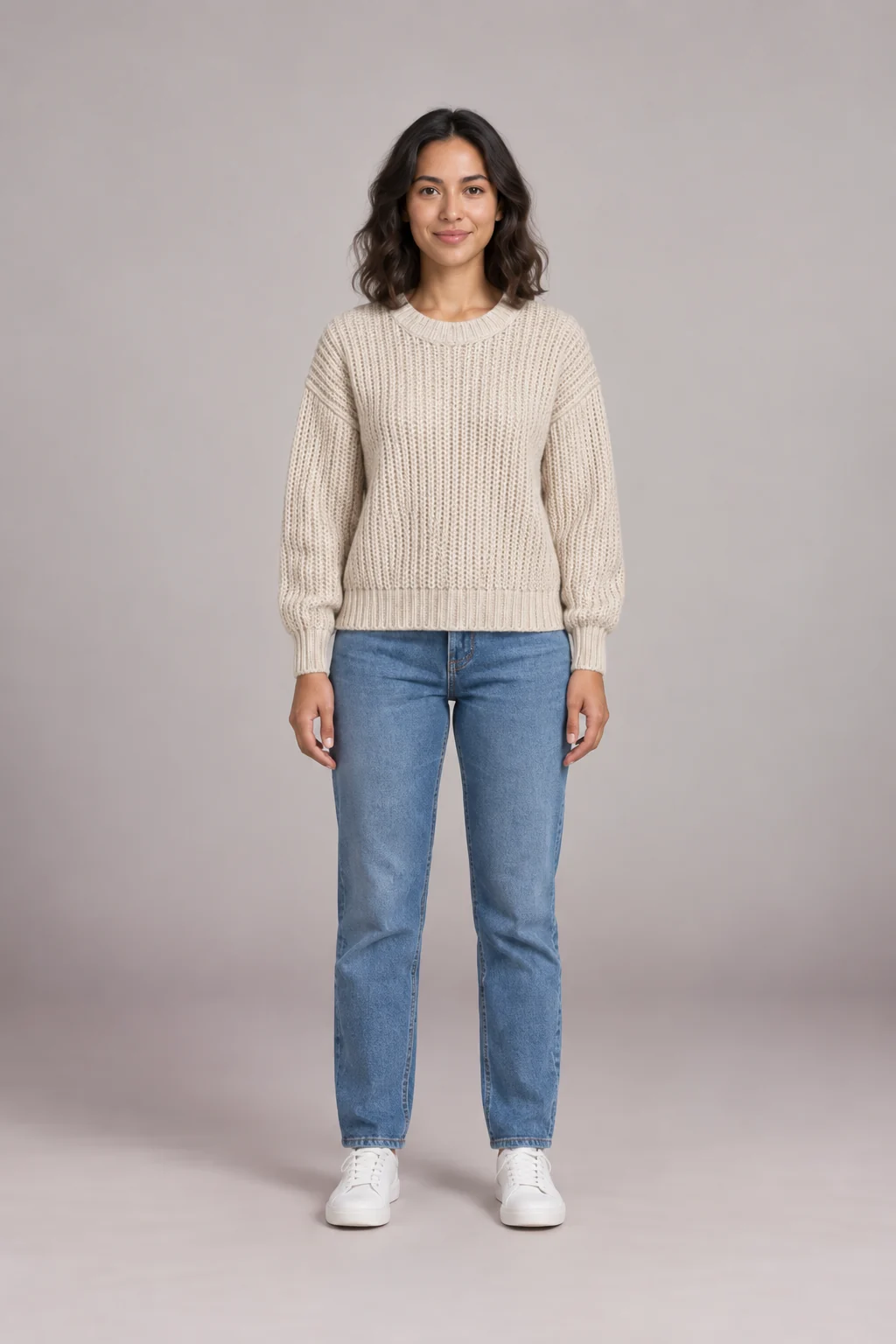 Woman in a cream knit sweater with jeans and white sneakers, rated for an everyday outfit