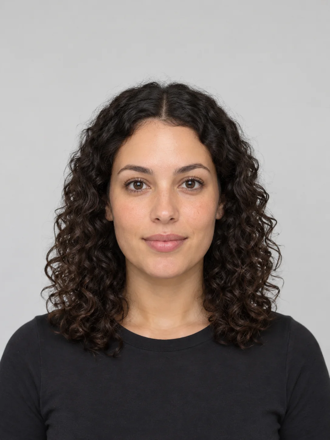 Adult woman with dark curly hair facing the camera, a sample for testing blush and eyeshadow